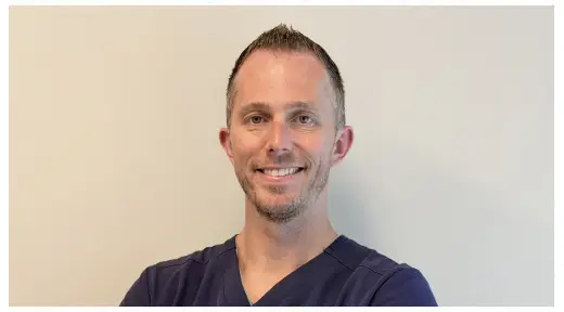 doctor in black shirt smiling in spike hair