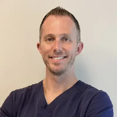 doctor in black shirt smiling in spike hair